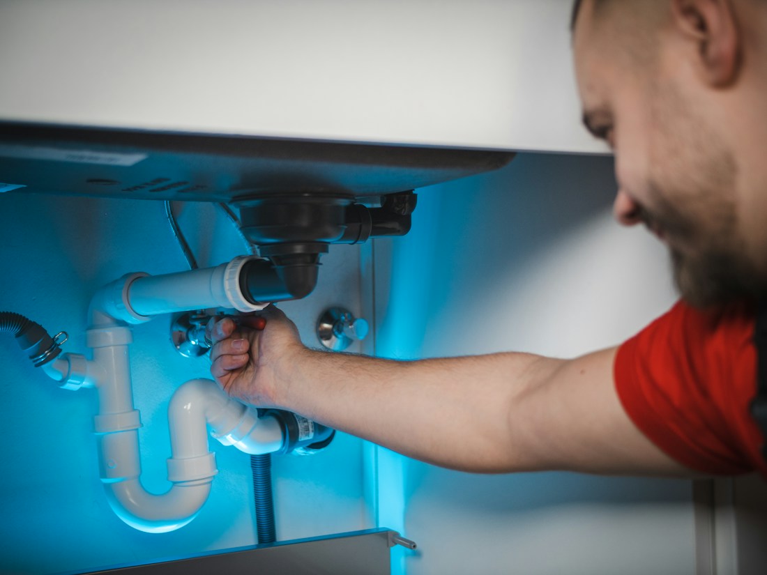 Plumber repairing the drain beneath a sink