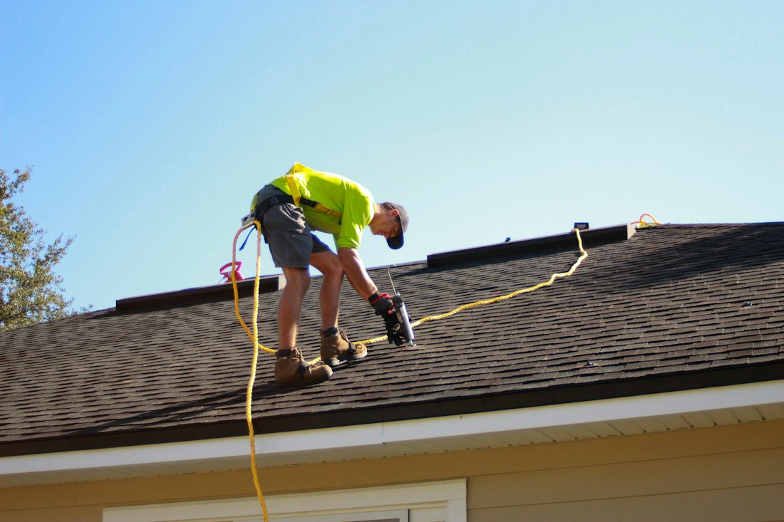 Roofer using a power tool on a shingle roof